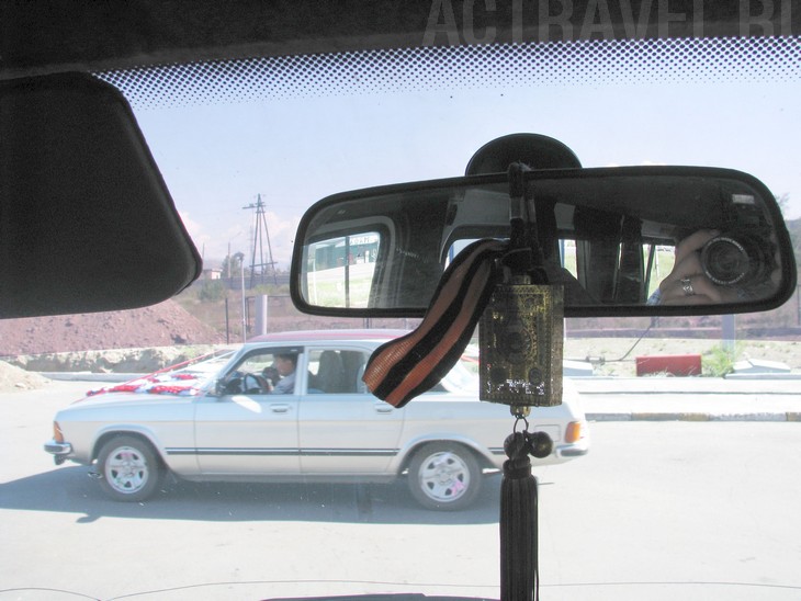 Фотография явно не удалась, поэтому объясняю на словах: на зеркале в салоне автомобиля подвешен буддистский амулет со свастиками, а к нему привязана георгиевская ленточка. Такого сочетания не увидишь больше нигде.